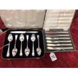 A cased set of six butter knives and a cased set of six spoons with fruit knife.