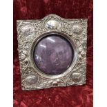 A silver picture frame with embossed decoration.