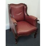 An early 20th Century wing back chair with studded leather upholstery.