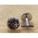 A pair of silver cufflinks with embossed image of the Sun and Moon.