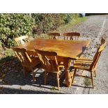 A contemporary large pine dining table and six pine farm house style chairs.