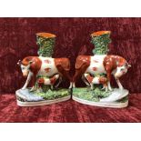 A pair of 19th Century Staffordshire flat back spill vases depicting a cow with feeding calf.