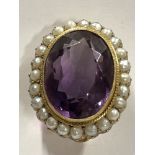 A 9ct gold brooch set with twenty four pearls surrounding a large central amethyst.