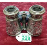 A pair of silver binoculars with floral scroll work decoration.