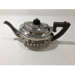 A small silver teapot with ribbed decoration.