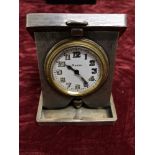 A silver cased eight day travel clock with engine turned decoration to the case.