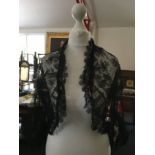 A jacket in black satine and organza and a black lace shrug.