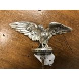 A white metal winged hood ornament believed to be a golden eagle.
