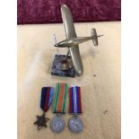 A WW2 brass stylised Spitfire with rotating propeller plus WW2 medal trio.