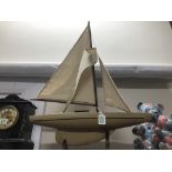 A model yacht under sail on a stand.