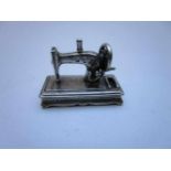 Zilveren miniatuur handnaaimachine met draaiend wiel Silver miniature sewing-machine