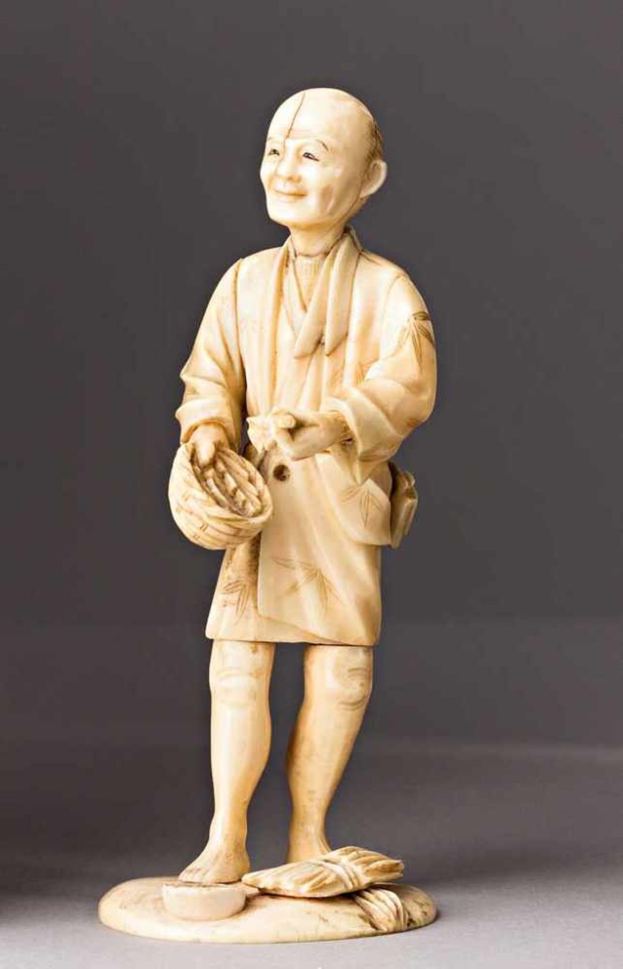 Mann mit Korb. Elfenbein. Ungedeutete Bodenmarke. Japan, 19. Jh. H 13,5 cm