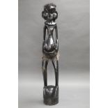 A CARVED EBONY TRIBAL FIGURE, MEASURING 97CM IN HEIGHT.