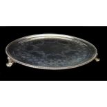 A circular silver salver, decorated with summer flower swags with a stiff leaf and star border,