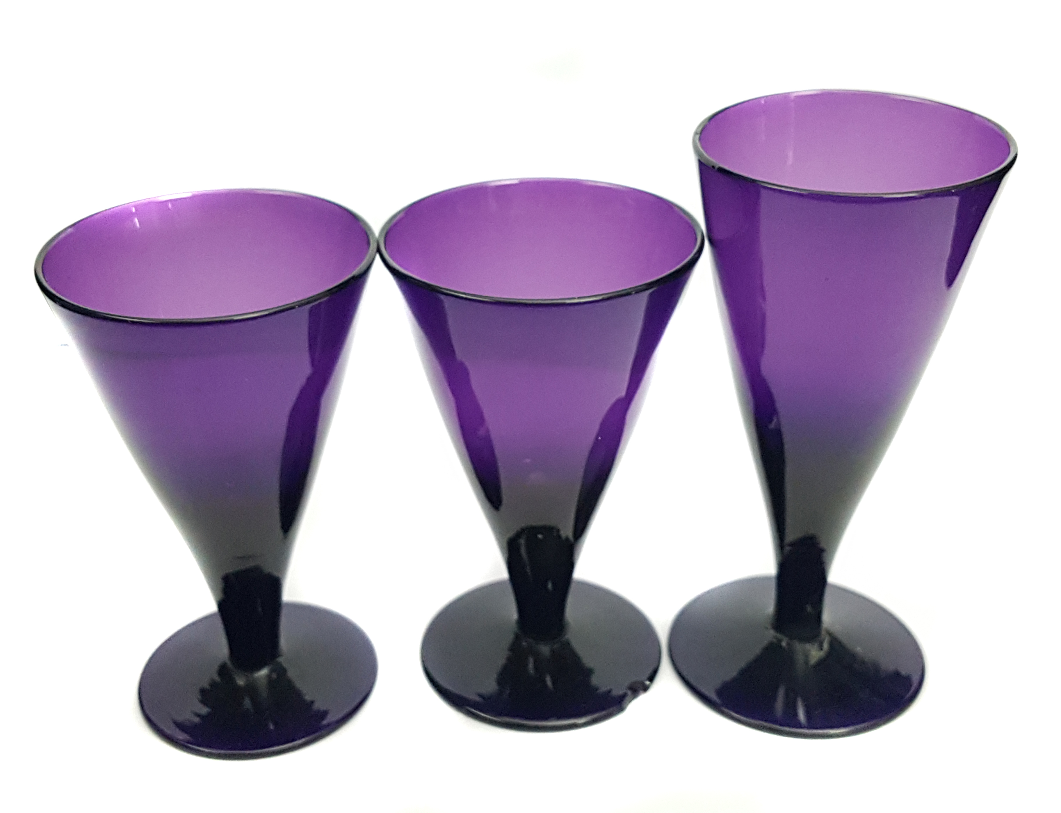 Three amethyst coloured glasses, conical on circular foot, 10cm max (3)