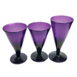 Three amethyst coloured glasses, conical on circular foot, 10cm max (3)