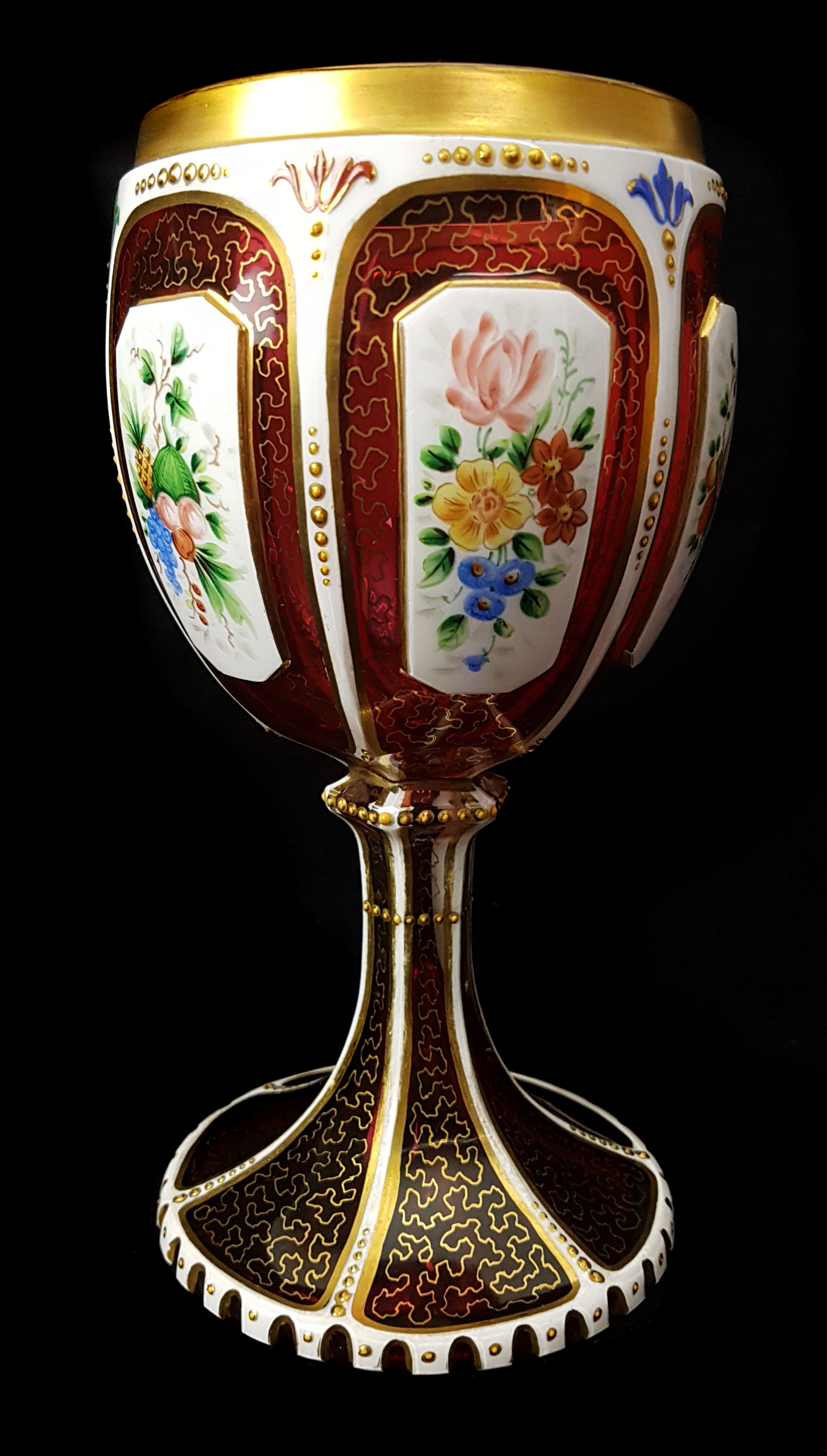 A Bohemian overlay glass goblet, c1850, white cut through to ruby with reserves, enamelled with