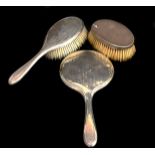 A silver backed hand mirror, striped engine turned decoration; a conforming hairbrush and one