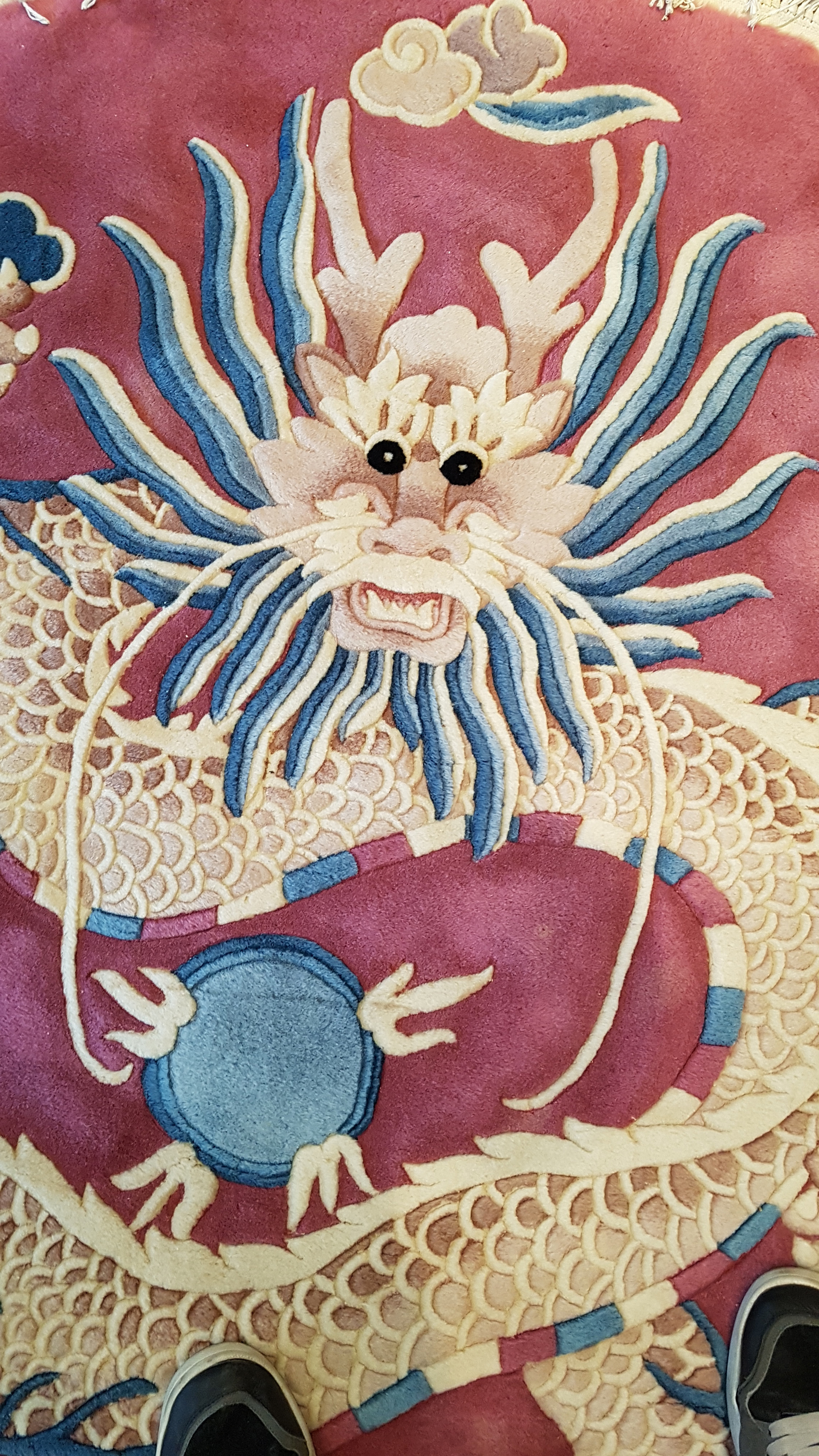 A Chinese circular wool rug, with a design of a scaly dragon, on a rose pink ground, 150cm diam