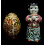 A Chinese porcelain figure of a standing sage with scroll; a figure of a child; and a pottery egg on