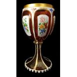 A Bohemian overlay glass goblet, c1850, white cut through to ruby with reserves, enamelled with