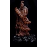 A Chinese bamboo carving of an immortal holding a large wrapped scroll, a crane to one side, eyes