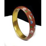 A Chinese cloisonne bangle decorated with a continuous floral garland on a claret ground, gilded