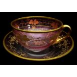 Moser - A graduated cranberry glass cup and saucer, gilded with scrolling vines, saucer 15.5cm max