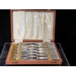 A cased set of six silver handled butter knives, stylised reeded pistol handles, stainless steel