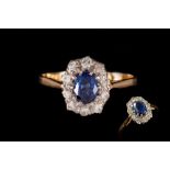 A SAPPHIRE AND DIAMOND CLUSTER RING, one oval cut sapphire of approx. 0.