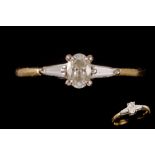 A DIAMOND SOLITAIRE RING, with oval cut diamond, flanked by tapered baguette cut diamond shoulders,