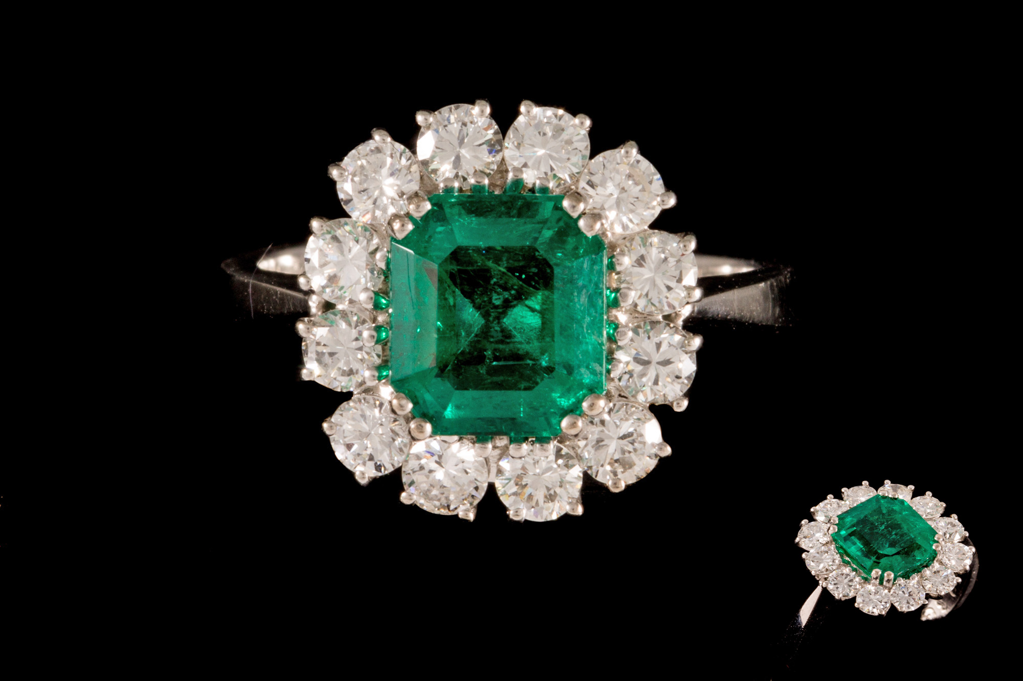 AN EMERALD AND DIAMOND CLUSTER RING, with one emerald of 2.