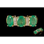 A THREE STONE EMERALD RING, set with diamond points,