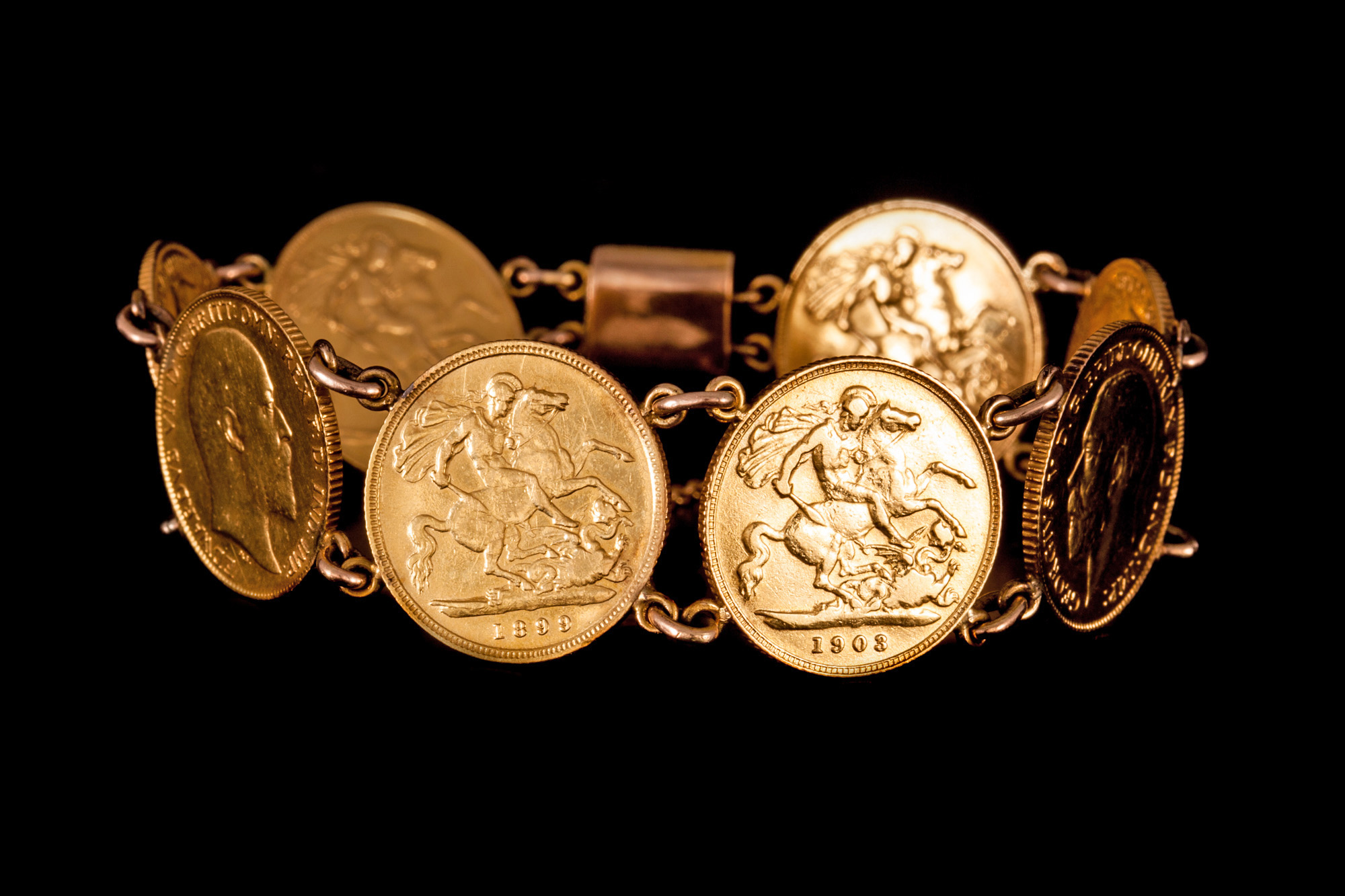 A HALF SOVEREIGN LINK BRACELET, with eight half sovereign coin links and floral engraved box clasp.