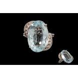 AN AQUAMARINE RING, flanked by diamonds,