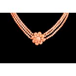 A CORAL BEAD NECKLACE, a three row uniform coral bead necklace with coral cluster centrepiece,