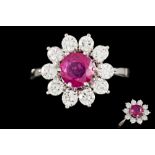 A RUBY AND DIAMOND DAISY CLUSTER RING, with one round cut ruby of 1.