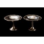 A PAIR OF GEORGE V SILVER COMPORTS, with shaped border, raised over circular stems,