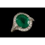 AN EMERALD AND DIAMOND CLUSTER RING, one oval cut emerald of approx 6.