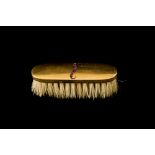 A 14CT GOLD BACKED MOUSTACHE BRUSH, with ruby moustache detail.