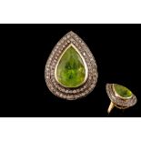 A PERIDOT AND DIAMOND CLUSTER RING, the pear shaped peridot of approx. 8.