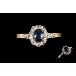 A SAPPHIRE AND DIAMOND CLUSTER RING, one oval sapphire cabochon of approx. 0.