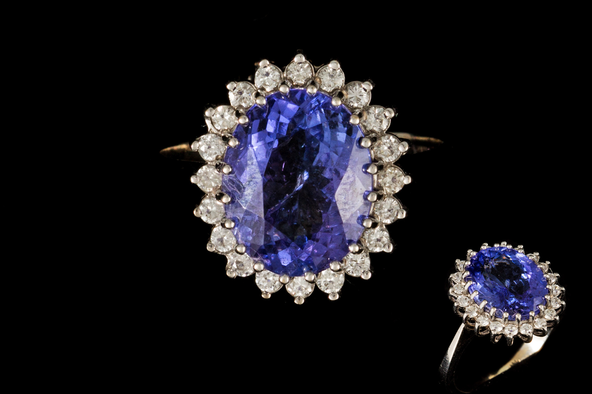 A TANZANITE AND DIAMOND CLUSTER RING, the oval tanzanite to a diamond surround,