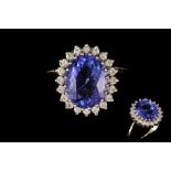 A TANZANITE AND DIAMOND CLUSTER RING, the oval tanzanite to a diamond surround,