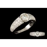 A DIAMOND SOLITAIRE RING, colet set with a brilliant cut diamond, to pavé diamond shoulders,