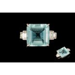 AN AQUAMARINE AND DIAMOND RING, the trap cut aquamarine to diamond set shoulders,