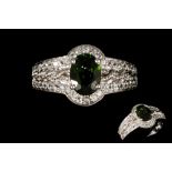 A PERIDOT AND DIAMOND CLUSTER RING, the oval peridot to a diamond surround and shoulders,