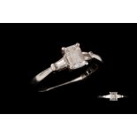 A DIAMOND SOLITAIRE RING, the emerald cut diamond to baguette diamond shoulders,