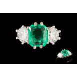 AN EMERALD AND DIAMOND THREE STONE RING, the octagonal cut emerald weighing 1.