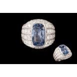 A SAPPHIRE AND DIAMOND 'BOMBE' RING, the cushion cut sapphire to a pavé set diamond platinum mount.